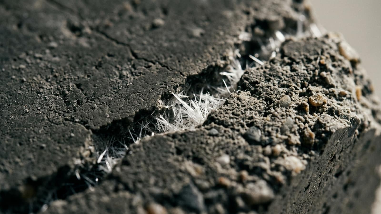 Kırılmış beton numunesinin makrosu: kılcal çatlağın içinde büyümüş beyaz iğnemsi kristaller